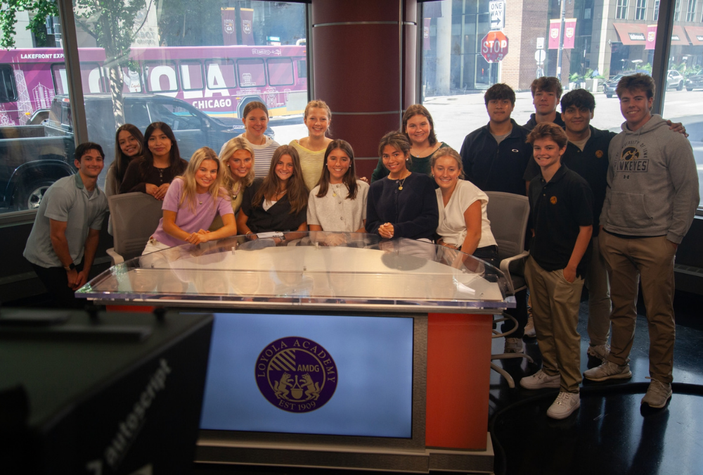 Loyola Academy students gather around the anchor desk inside the SoC